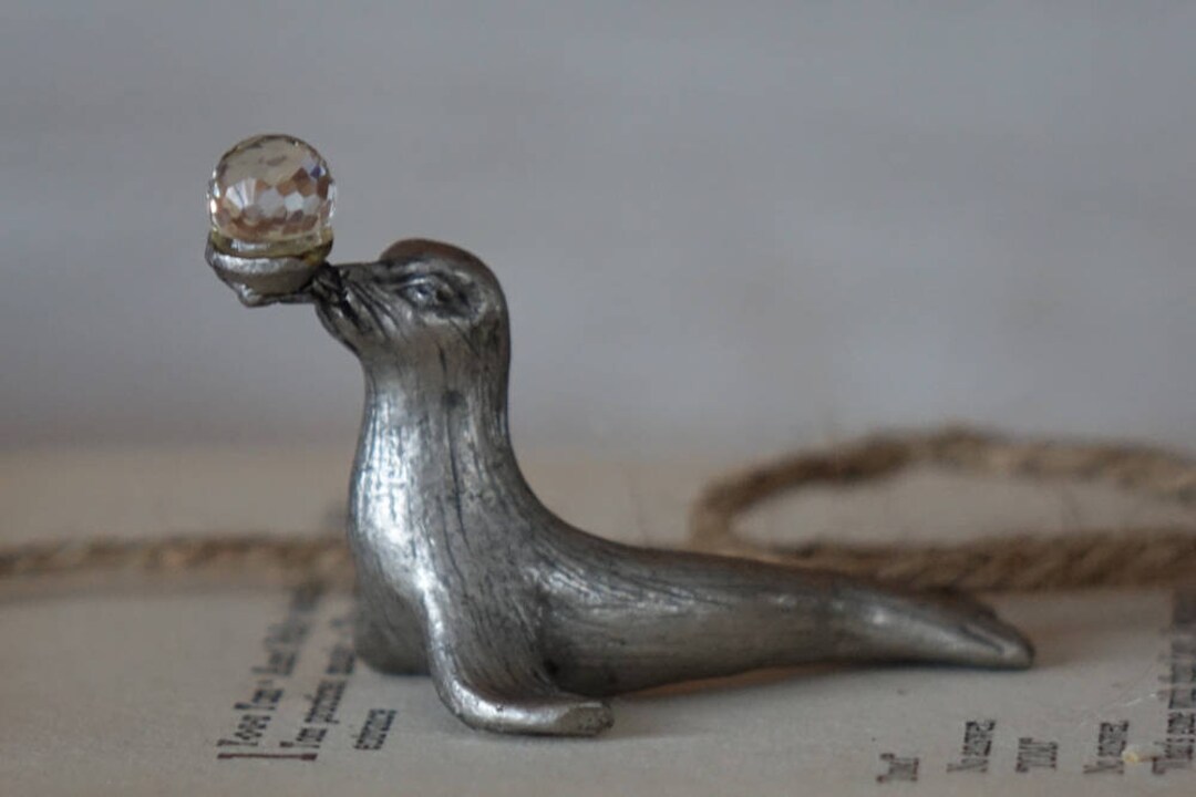 A pewter seal figurine balancing a crystal ball on its nose